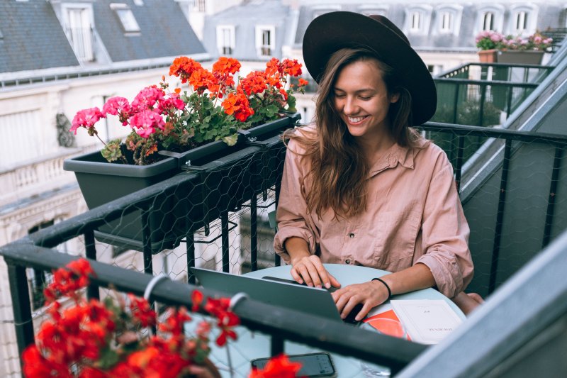Una mujer hacer teletrabajo con el ordenador portátil en en balcón de su casa
