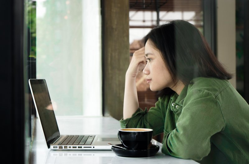 Una mujer está ante el ordenador portátil en una cafetería y mira ofertas de empleo porque busca trabajo aunque ya está ocupada