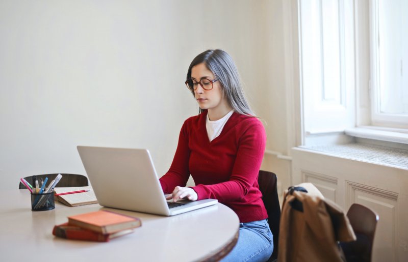 Un mujer que trabaja en casa escribe en el ordenador portátil para mejorar su comunicación escrita