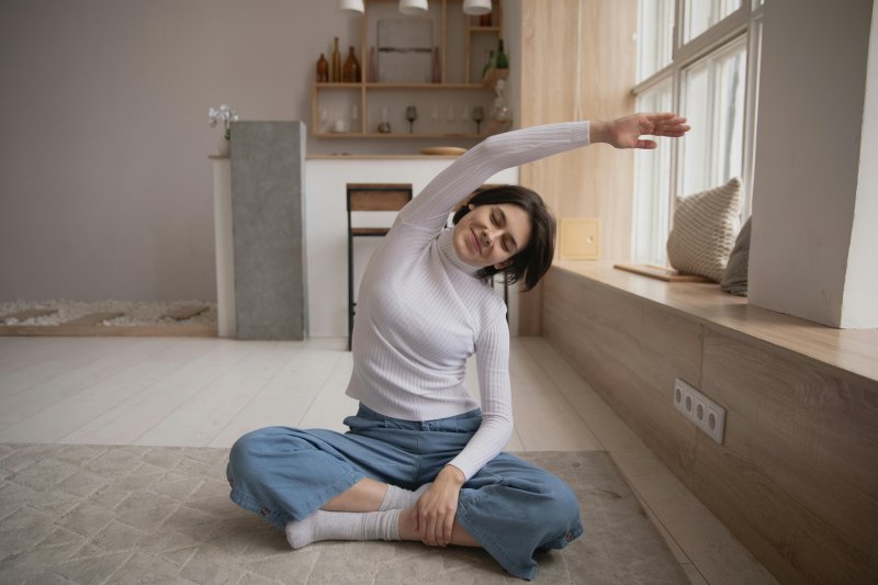 Una mujer que hace teletrabajo realiza ejercicios de estiramiento y relajación en su casa