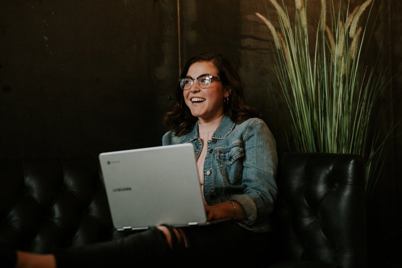 Una mujer con el ordenador portátil ríe y muestra emociones positivas con el equipo de trabajo