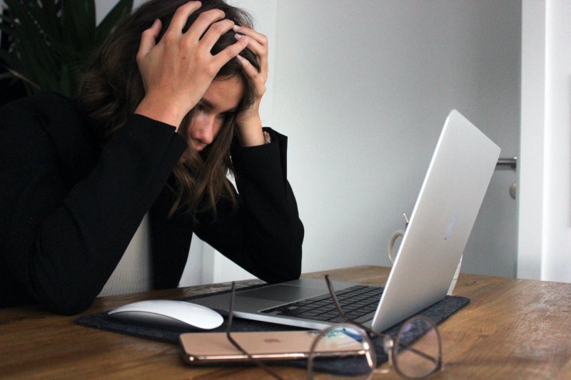 Una mujer se pone las manos en la cabeza delante del ordenador portátil después de cometer un error