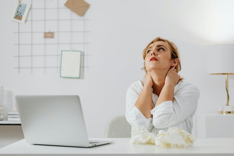 Teletrabajadora se toca el cuello y mira hacia el techo como señales de padecer estrés y ansiedad