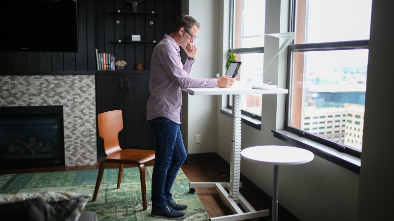 Un hombre utiliza una mesa de pie para trabajar en su casa