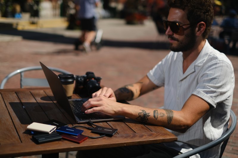 Un fotógrafo utiliza el ordenador portátil en el exterior para guardar las fotografías en el disco duro del dispositivo informático