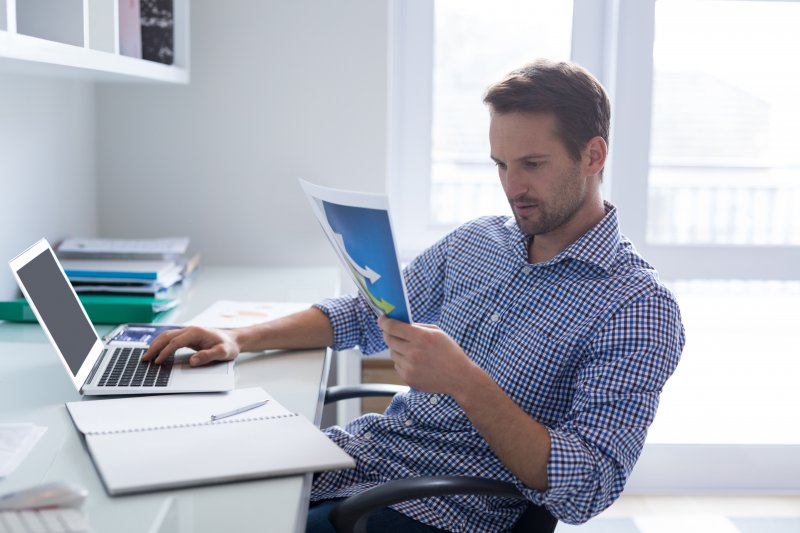 Un hombre en su oficina en casa utiliza un método para leer más rápido un documento para que su jornada laboral sea más productiva
