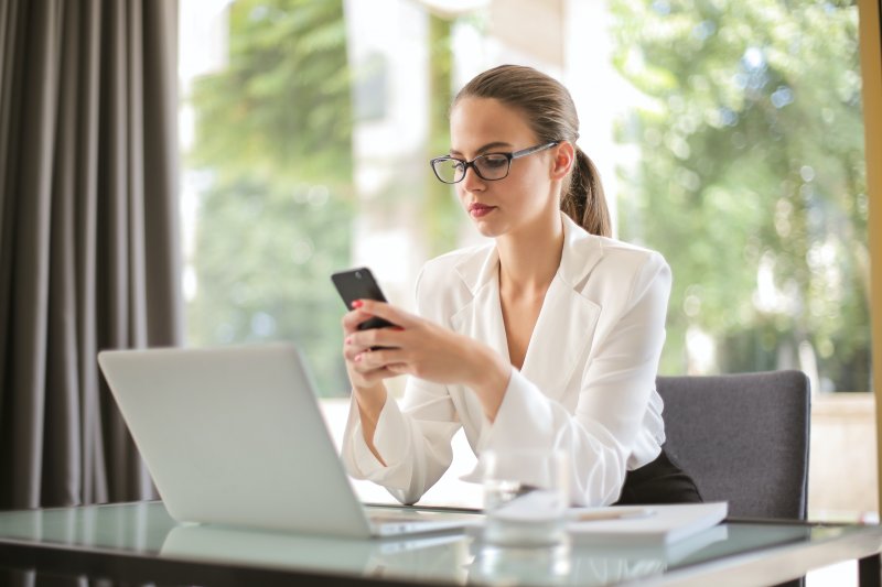 Una mujer escribe en el teléfono móvil para tener actualizada su marca personal en el ámbito profesional