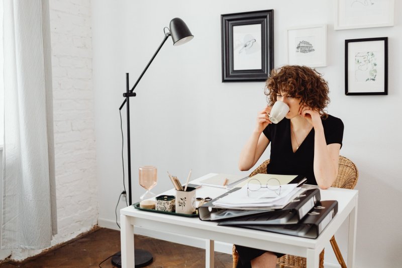 Una teletrabajadra toma una taza de café mientras utiliza el Método de acción para organizarse mejor en su home office