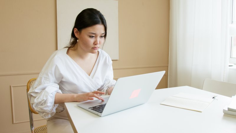 Una teletrabajadora que escribe en el ordenador portátil tiene la piel seca por efecto del aire acondicionado que tiene instalado en la oficina en casa