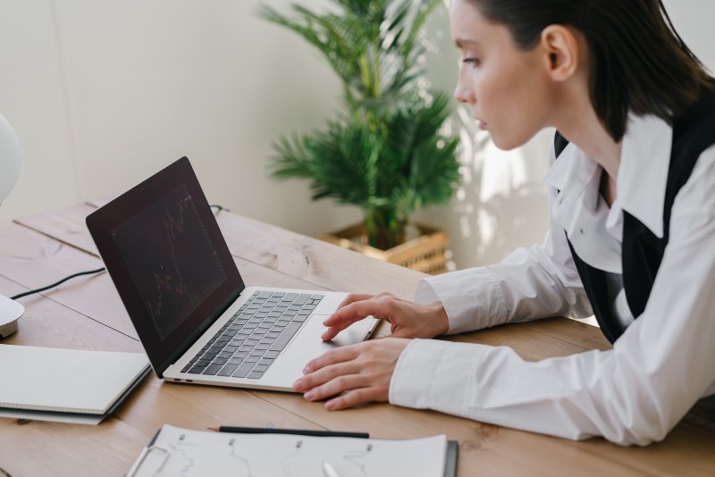 Una mujer que hace trabajo remoto desde su casa escribe en el ordenador portátil