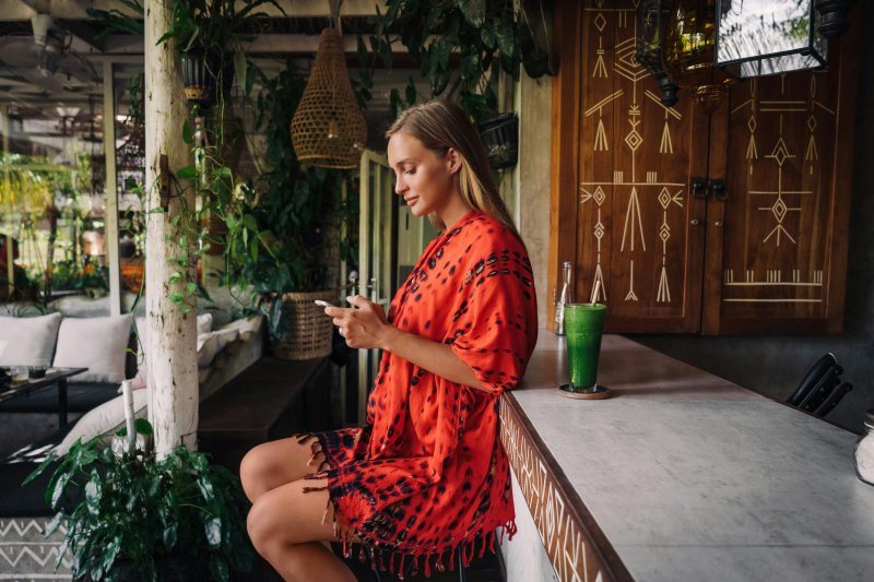 Una mujer utiliza la red wifi de un bar en el teléfono móvil mientras está de vacaciones