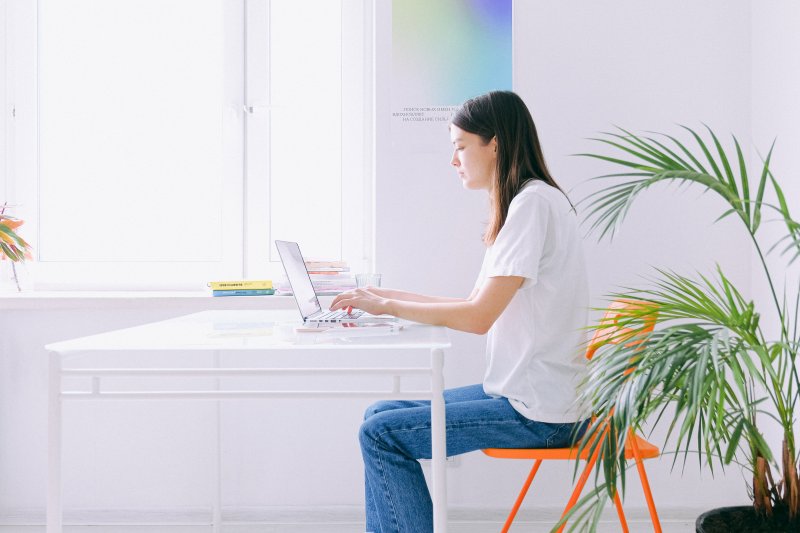 Una mujer escribe con el ordenador portátil en su oficina en casa ecológica i sostenible