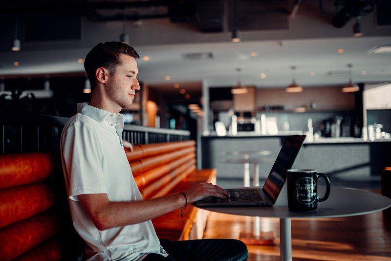 Un hombre utiliza el ordenador portátil en una cafetería mientras se toma un café