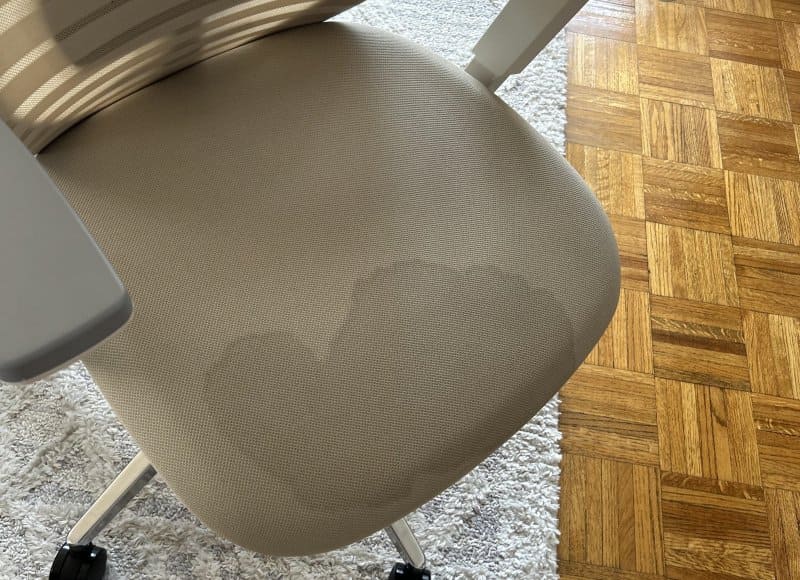 Silla de oficina ergonómica con manchas de sudor en el asiento a causa de la mala transpiración en el trasero