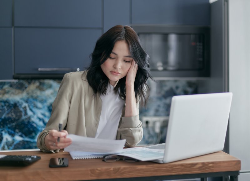 Una teletrabajadora nota que tiene exceso de información mientras lee un documento y utiliza el ordenador portátil