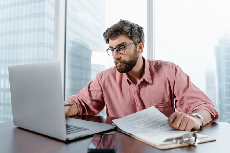 Un hombre que hace trabajo híbrido utiliza el ordenador portátil en las oficinas de la empresa